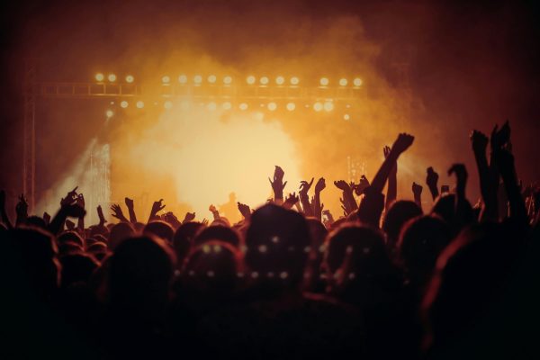 Energetic music concert with a vibrant crowd cheering under bright stage lights.