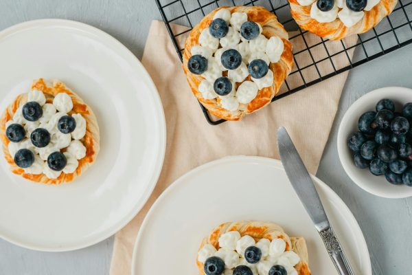 Freshly baked blueberry tarts with cream cheese frosting arranged on a table for a delightful snack.